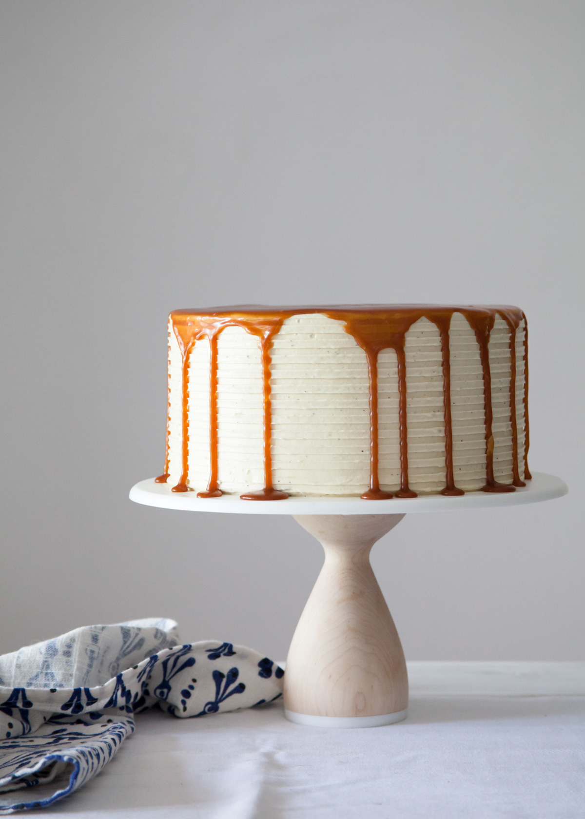 A London Fog cake on a cake stand with dripping caramel sauce