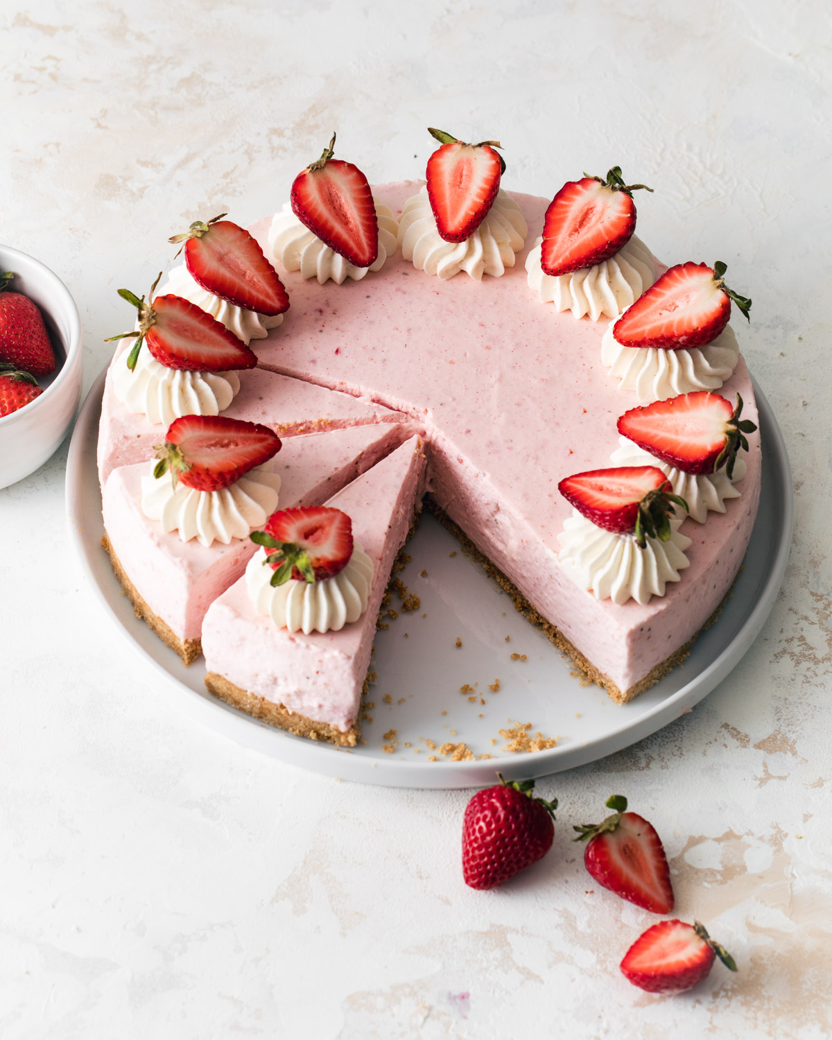 A no-bake strawberry cheesecake on a platter with fresh strawberries on top