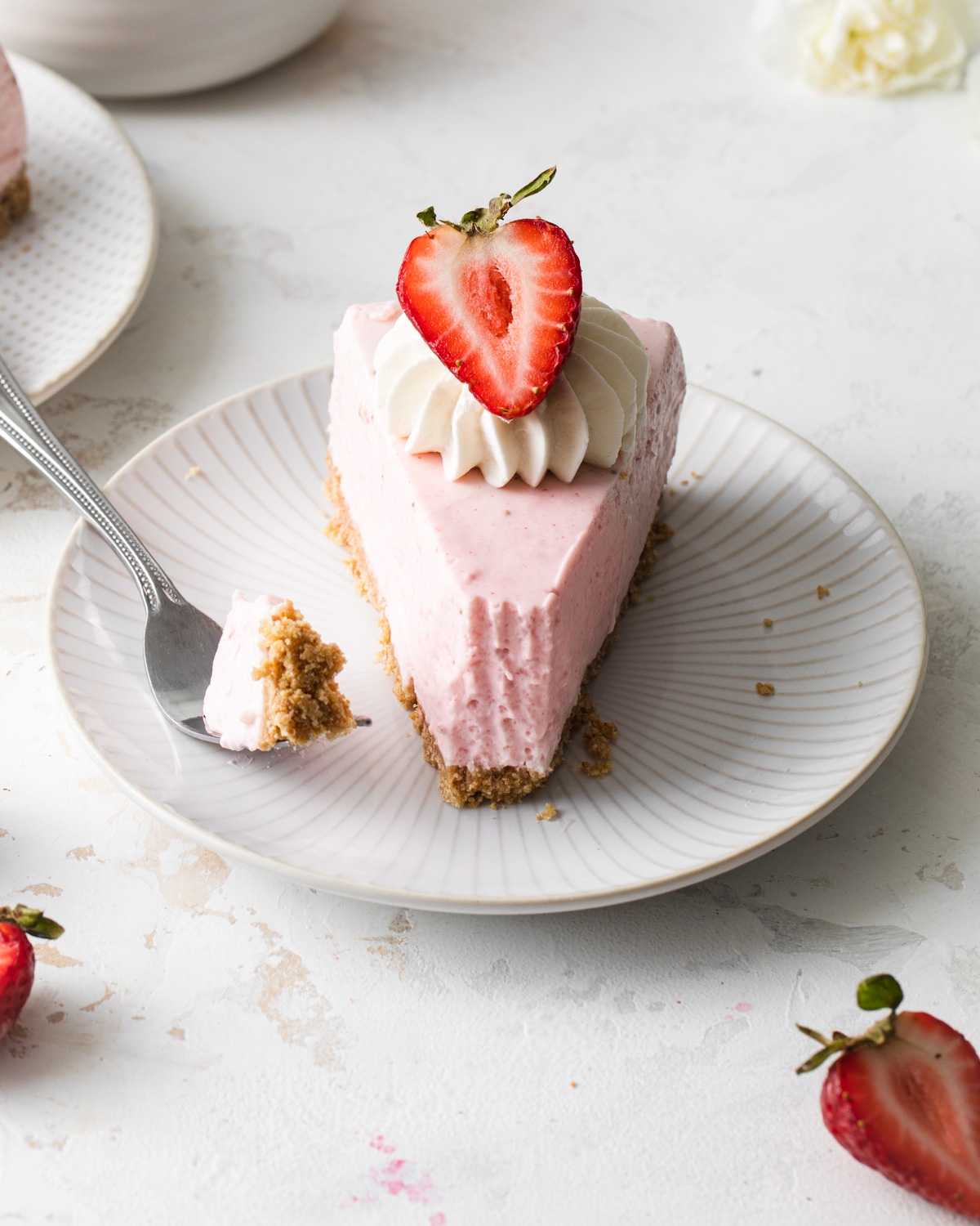 A slice of no-bake strawberry cheese with a fresh strawberry on top