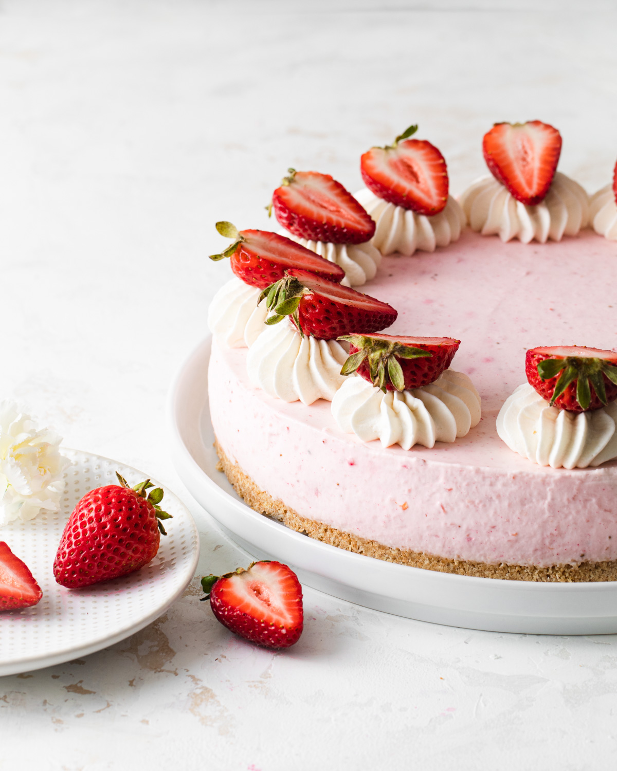 A no-bake strawberry cheesecake on a platter with fresh strawberries on top