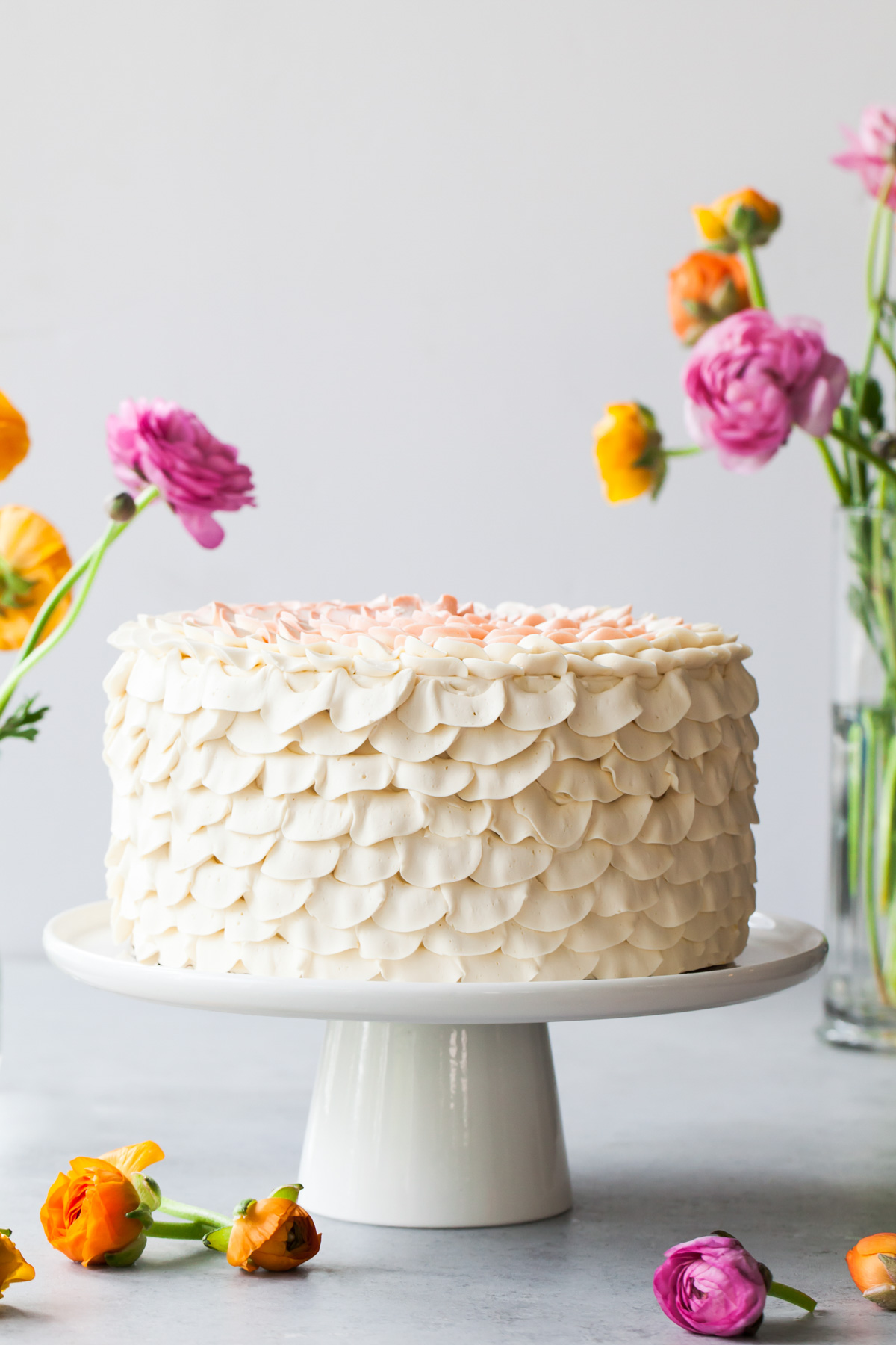 An orange salted honey cake with petal piped buttercream on a cake stand