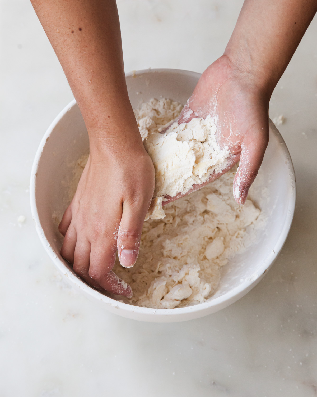 cutting in the butter with hands to make pie dough