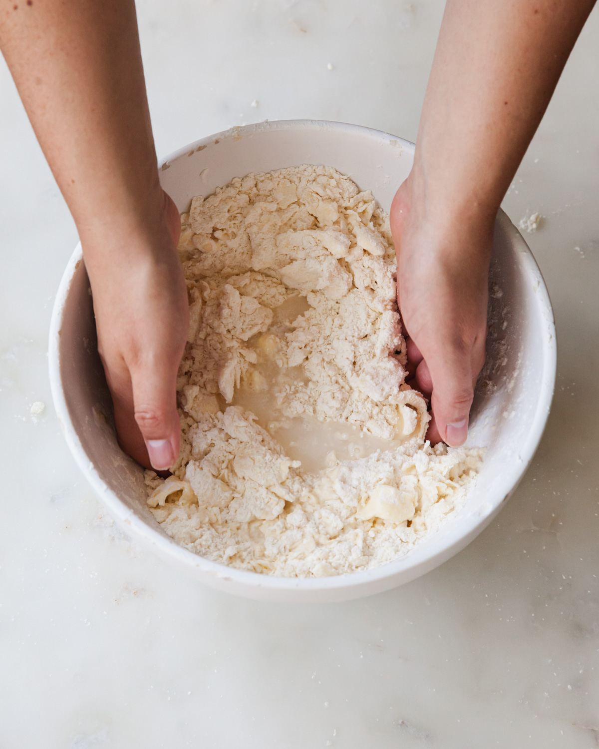 mixing butter, flour, and water with hands to make pie dough