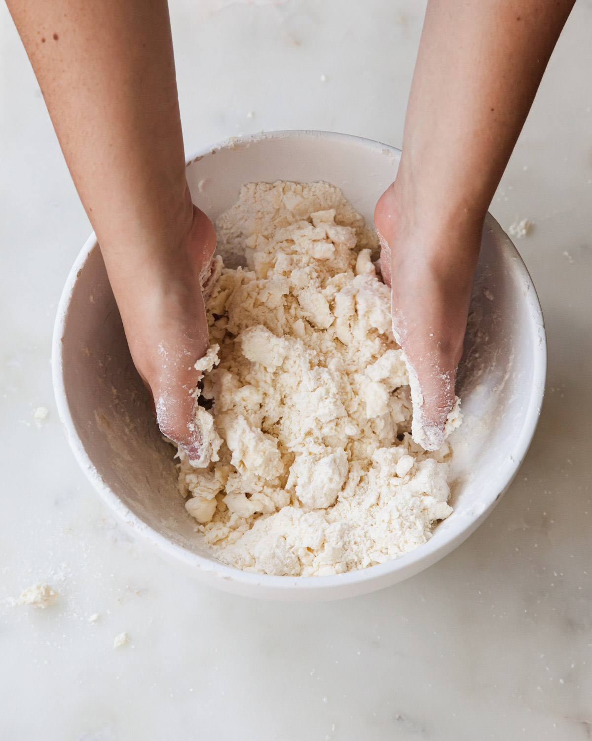 mixing together pie dough by hand in a mixing bowl