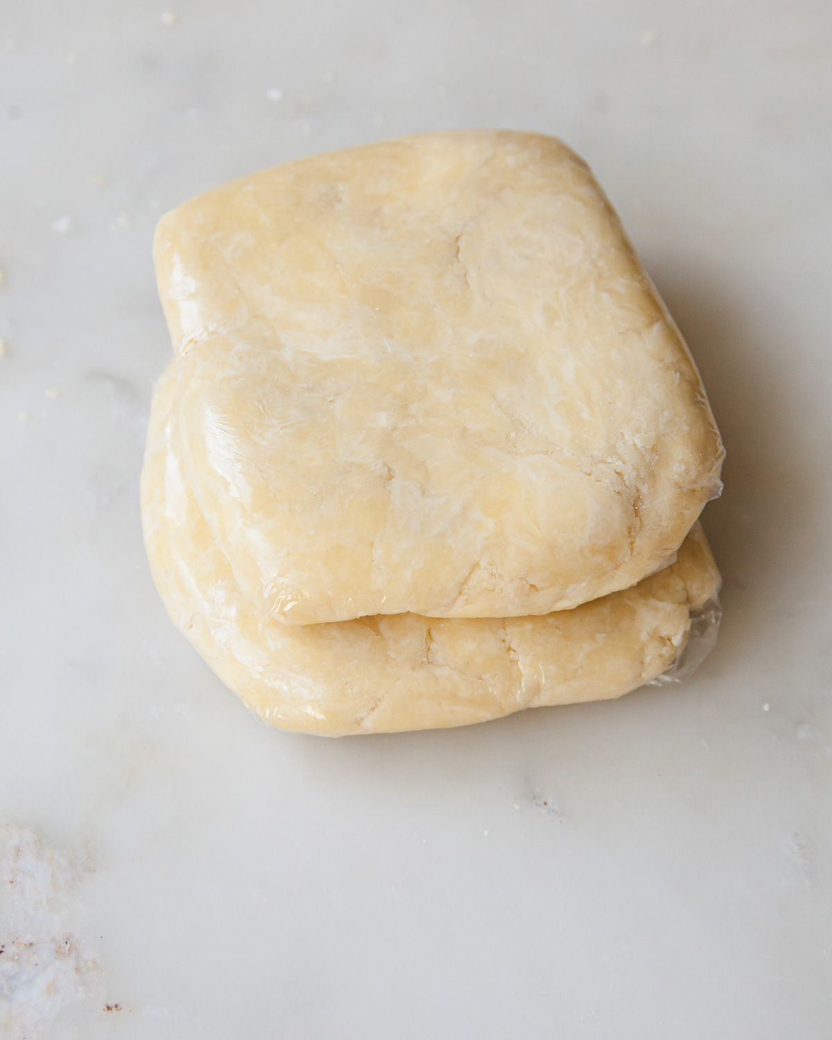 prepared pie dough by hand wrapped in plastic