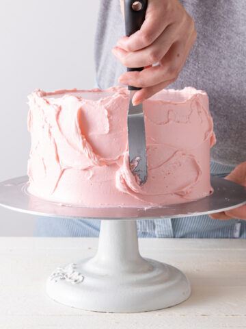 Frosting a pink cake with an offset spatula