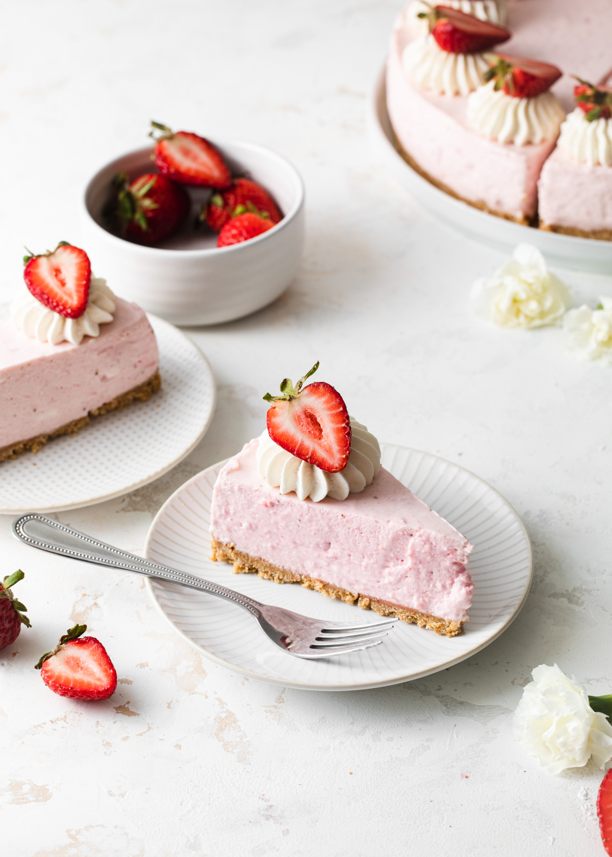 A slice of no-bake strawberry cheese with a fresh strawberry on top