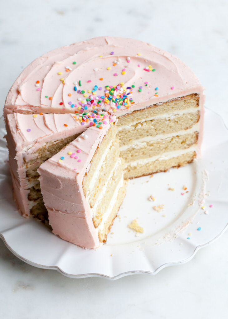 A three-layer vanilla bean cake with pink buttercream and sprinkles on top