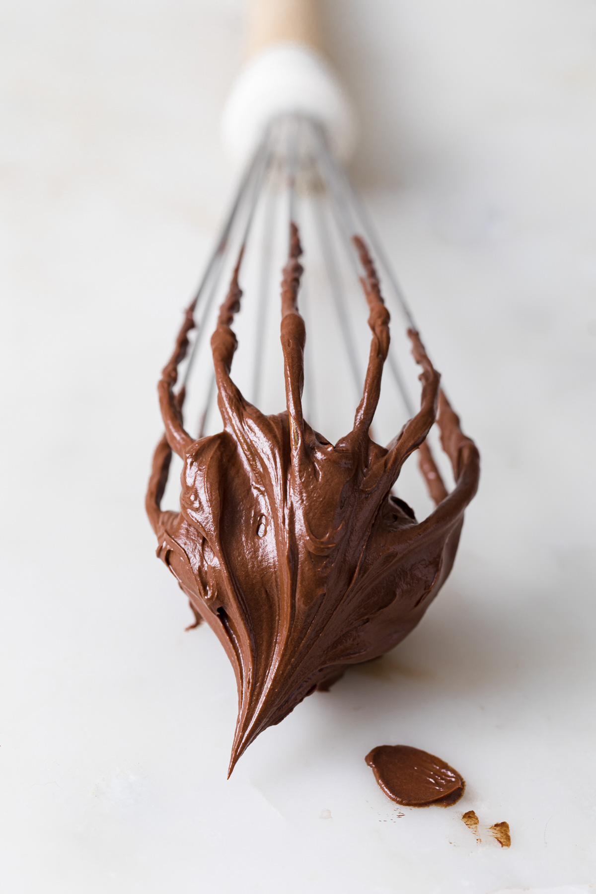 A whisk with whipped chocolate ganache