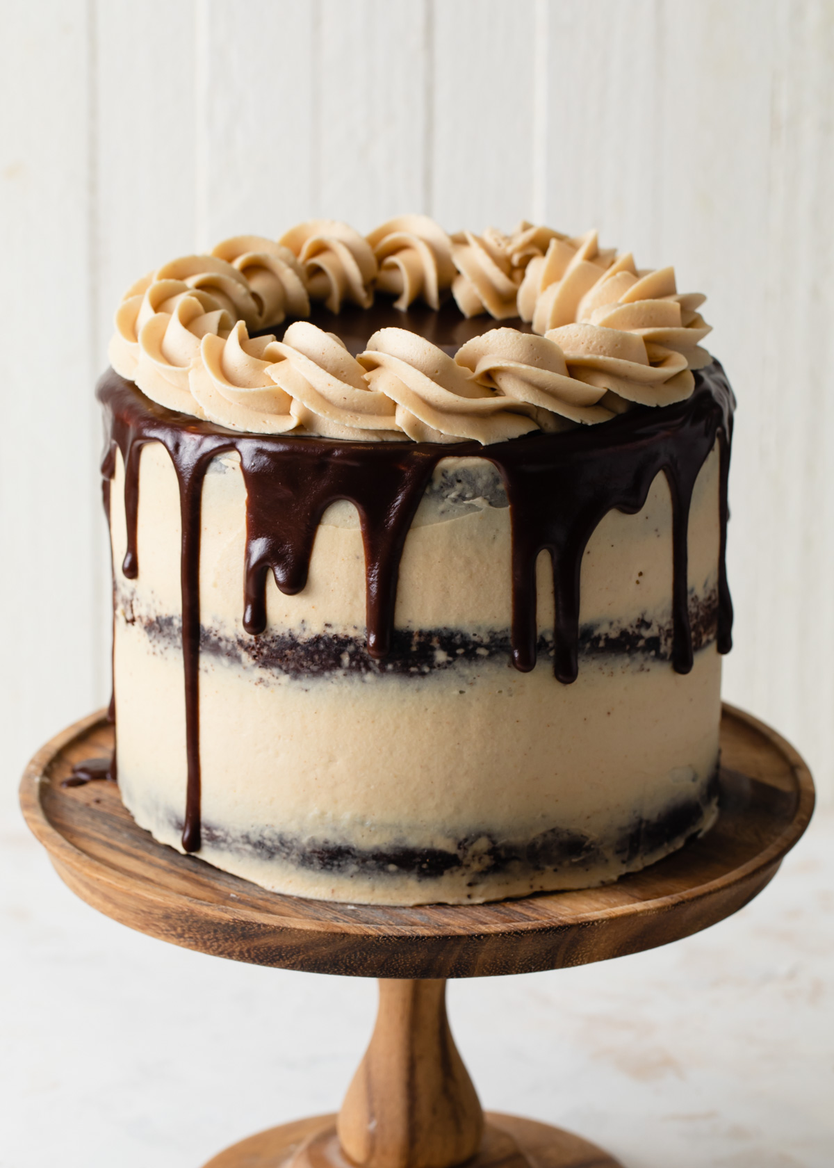 A three-layer chocolate cake with peanut butter frosting on a cake pedestal
