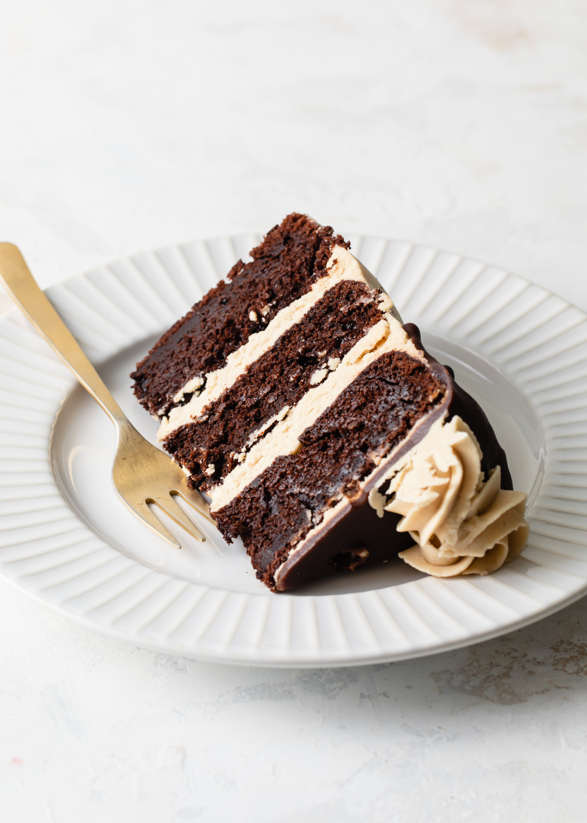 A slice of three-layer chocolate cake with peanut butter buttercream
