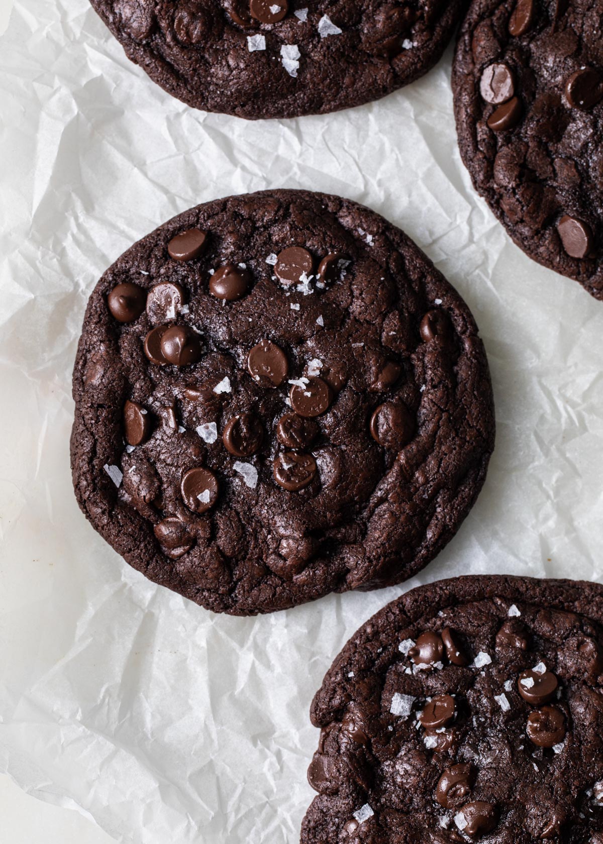 Baked double chocolate chip cookies on a piece of parchment paper