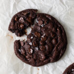 A giant double chocolate chip cookie baked on a piece of parchment paper