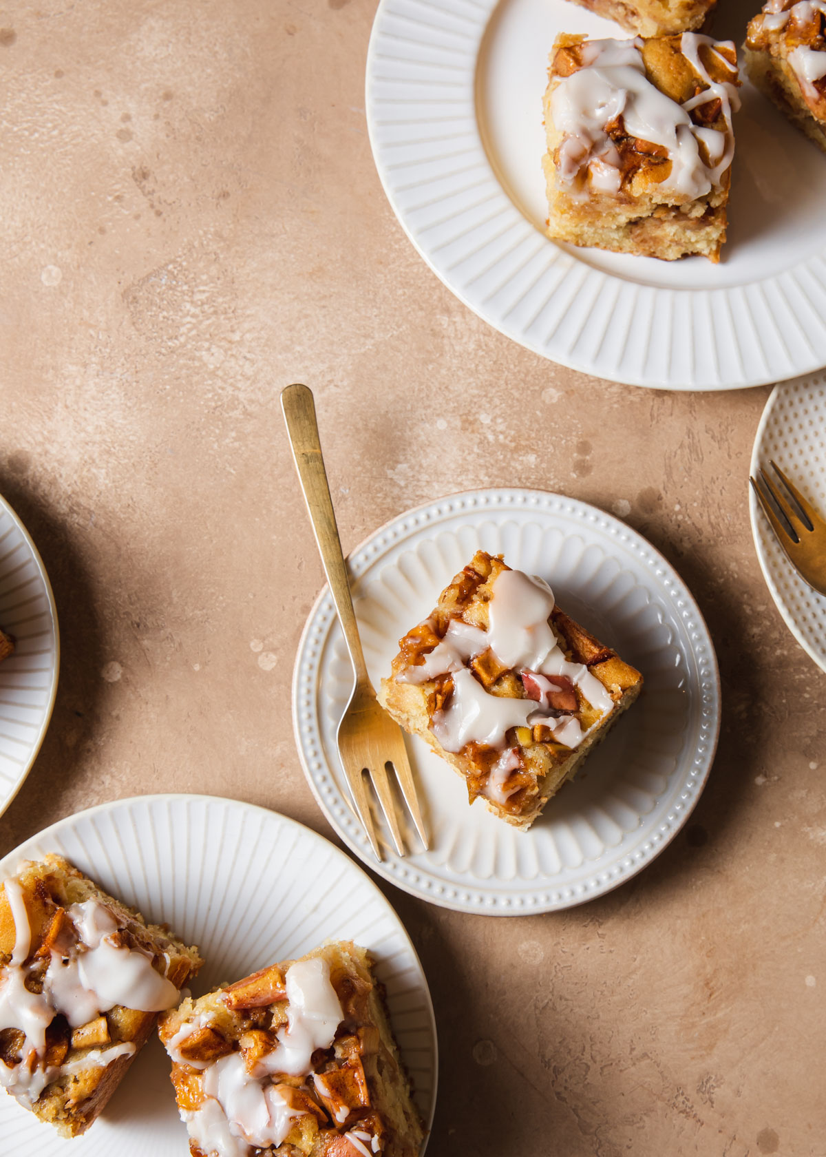 An overhead image of apple cake squares on white plates
