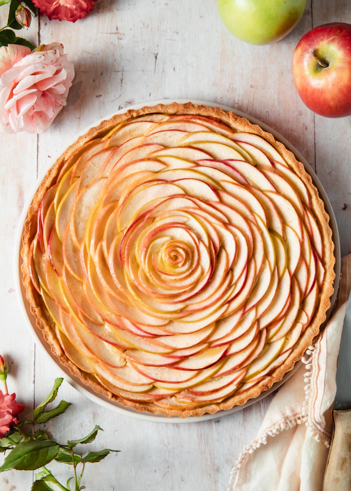 A baked apple tart with almond filling and a rose pattern on top
