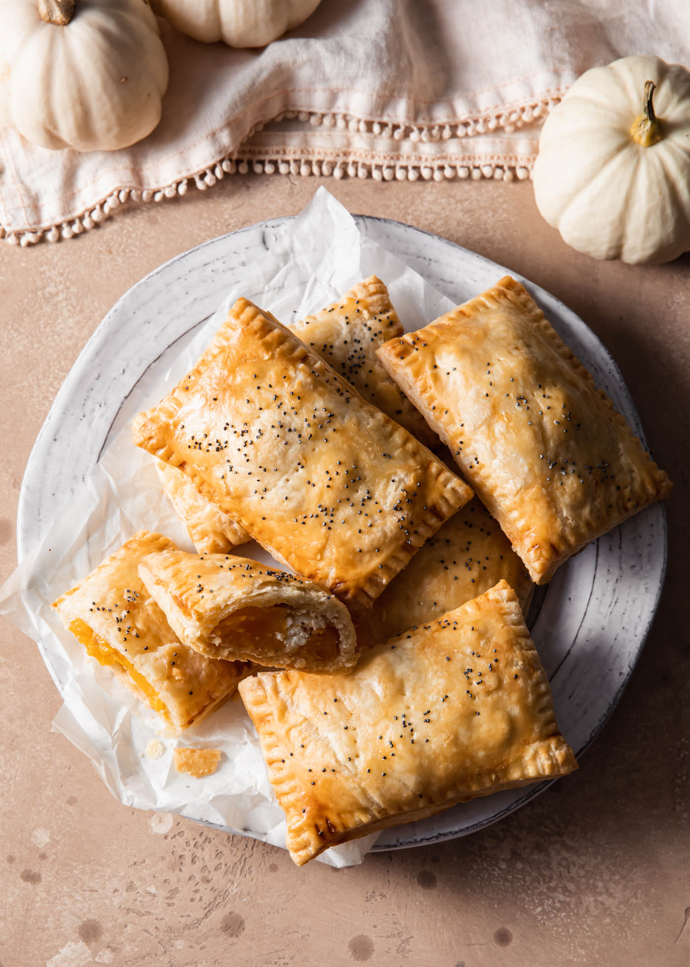 A plate of butternut squash hand pies on a table with mini pumpkins