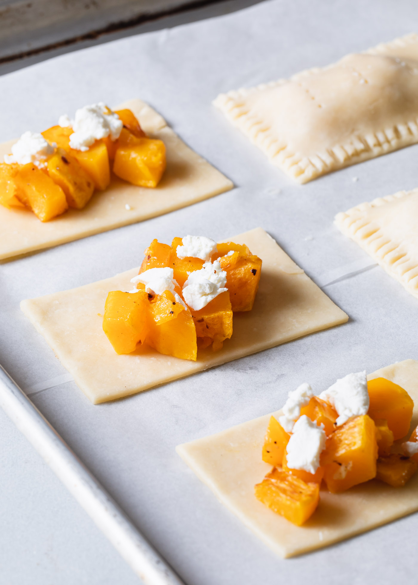 Butternut squash hand pies being assembled on a baking sheet