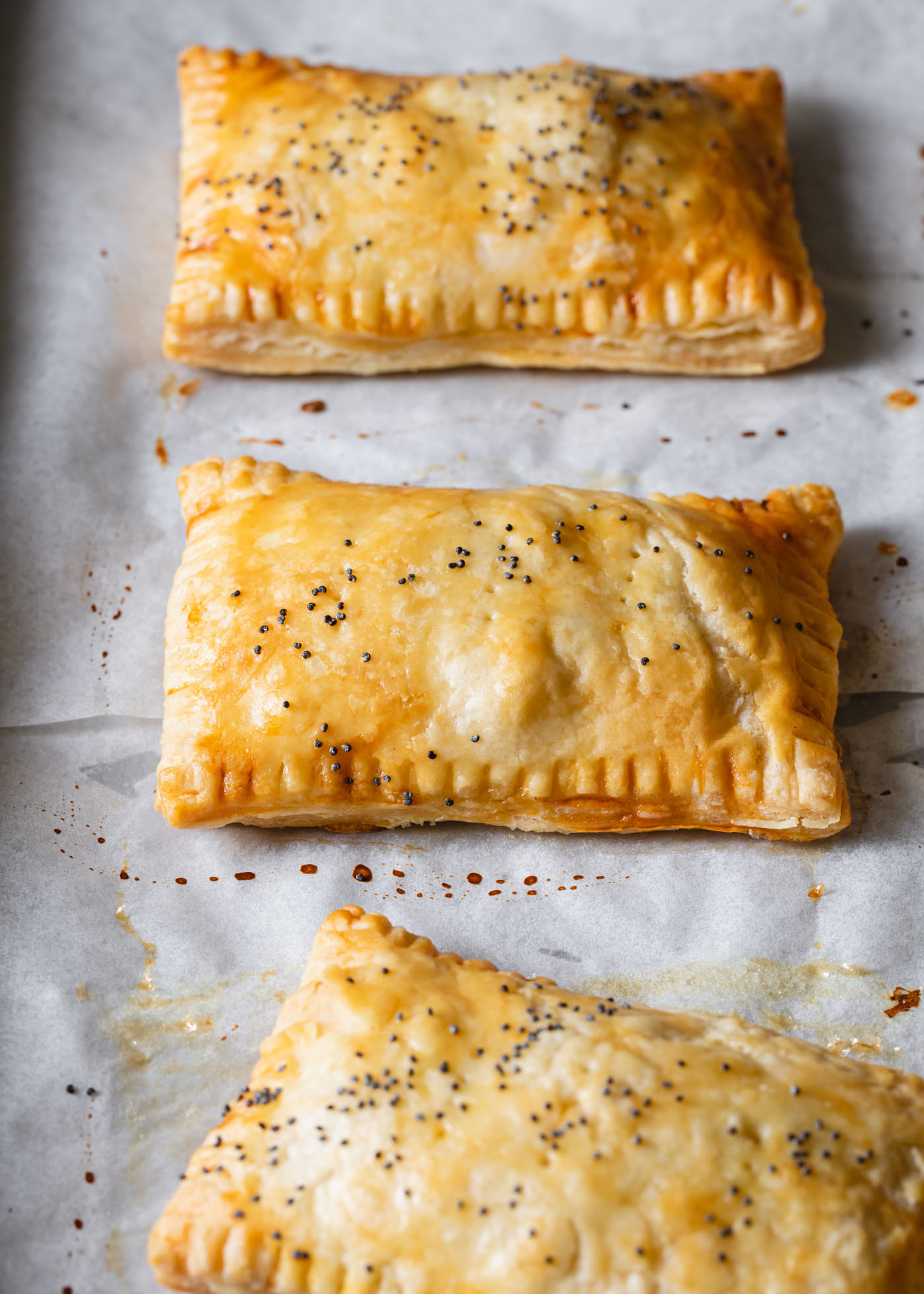 Baked butternut squash hand pies on a baking sheet with parchment paper