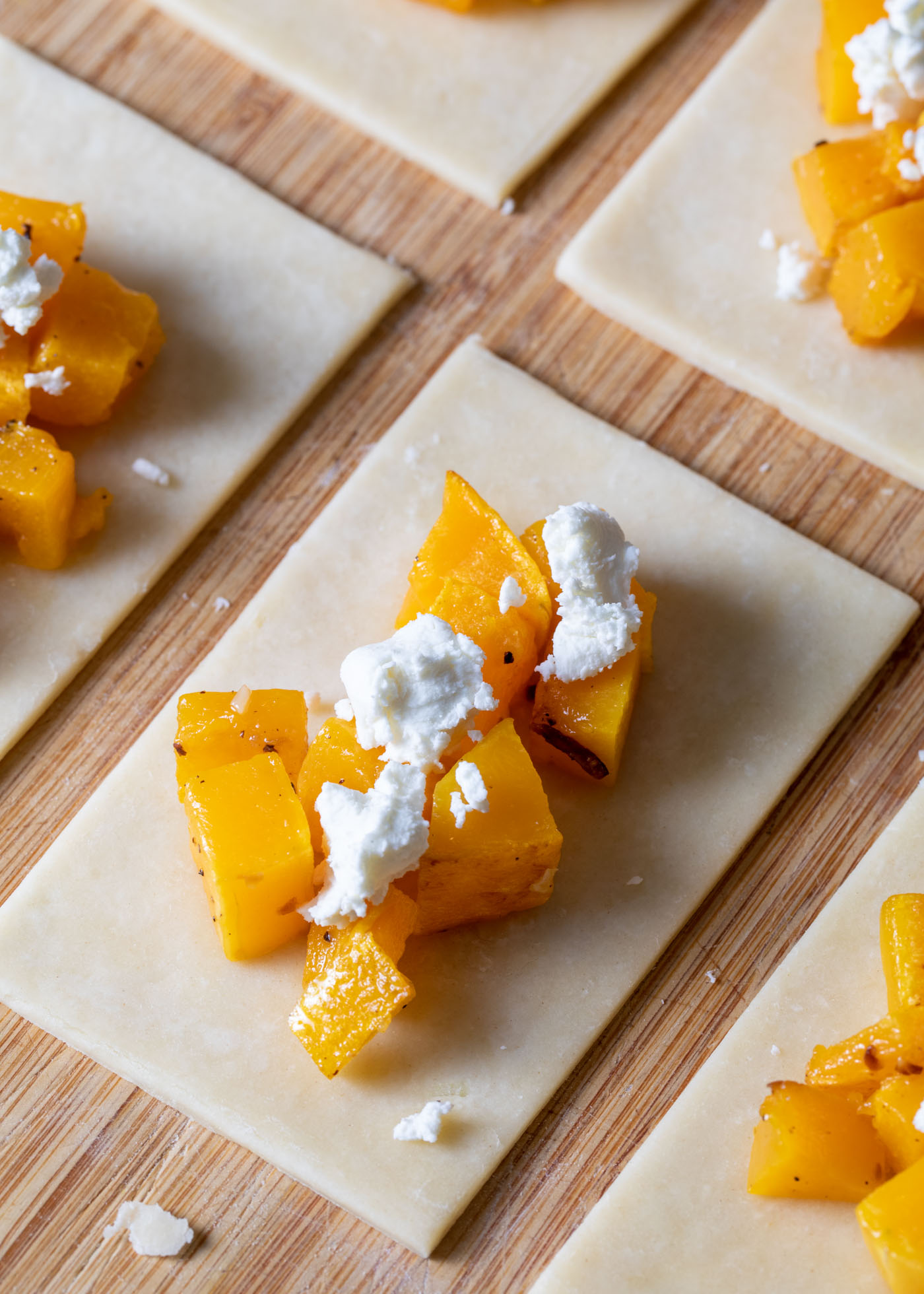 Assembling butternut squash hand pies with goat cheese on top