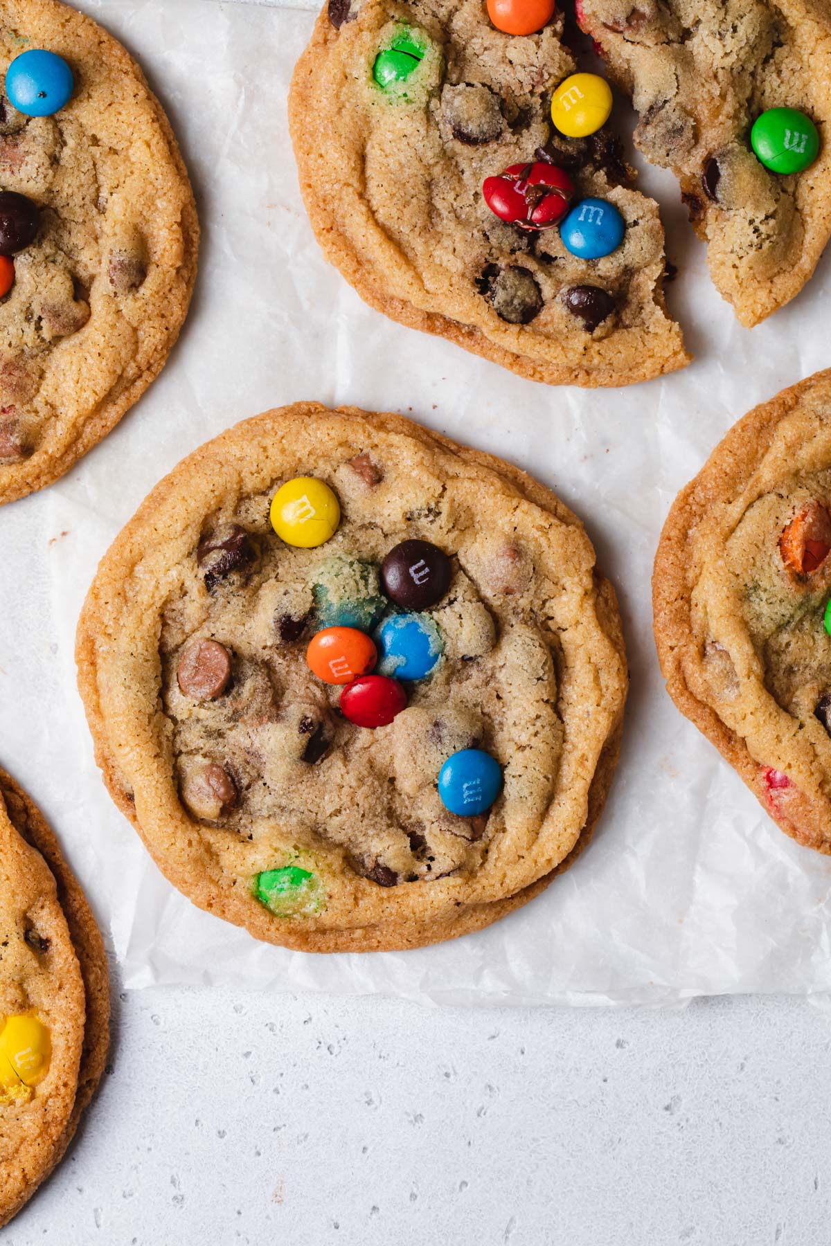 An overhead image of baked rainbow m and m chocolate chip cookies on a piece of parchment paper
