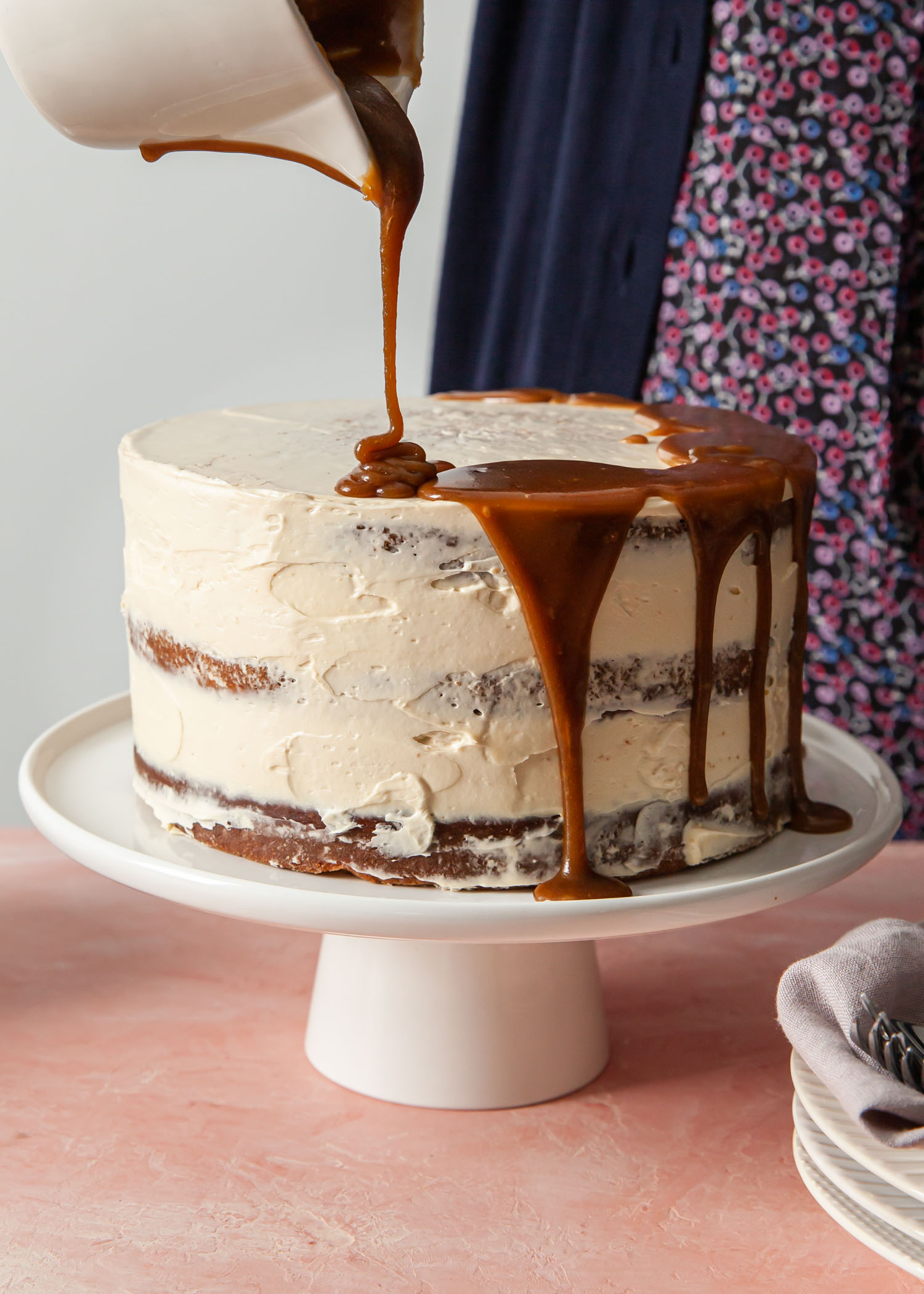 Pouring toffee sauce on a sticky toffee layer cake
