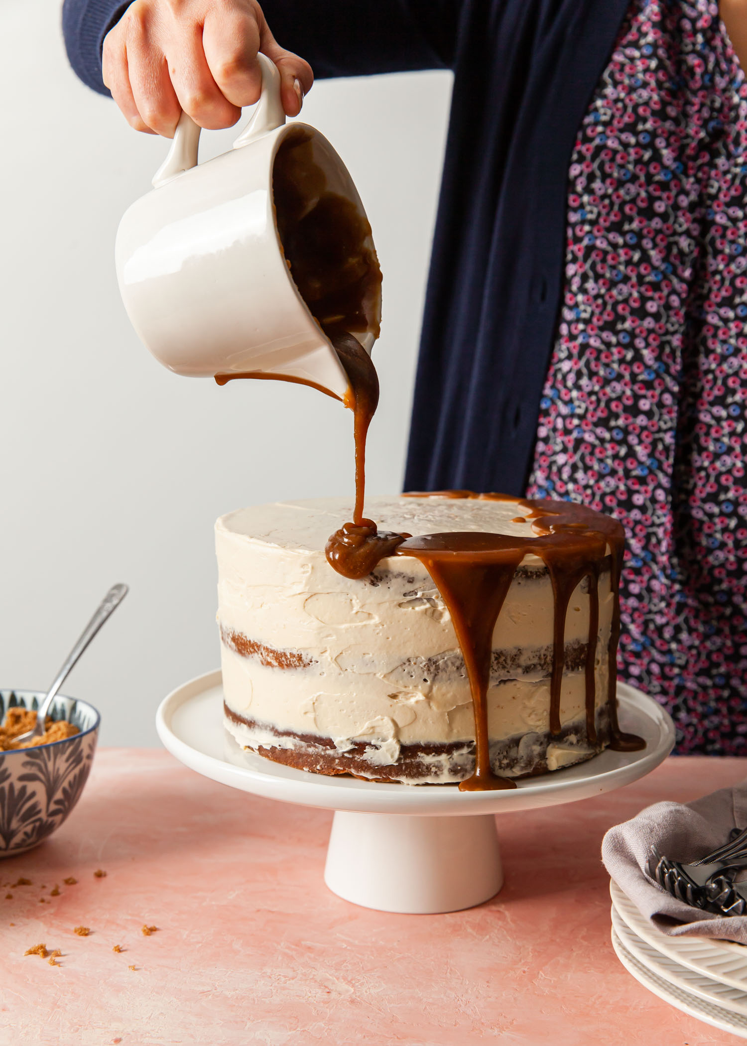 Pouring toffee sauce on top of a layer cake