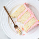 Fluffy white cake with pink buttercream on a plate.