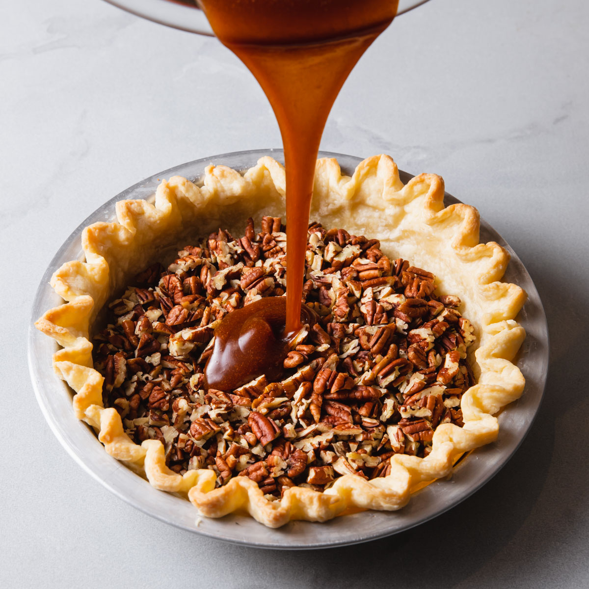 Pouring filling into a pecan pie