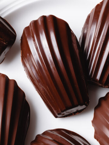 A close-up of chocolate Madeleines with a shiny chocolate glaze