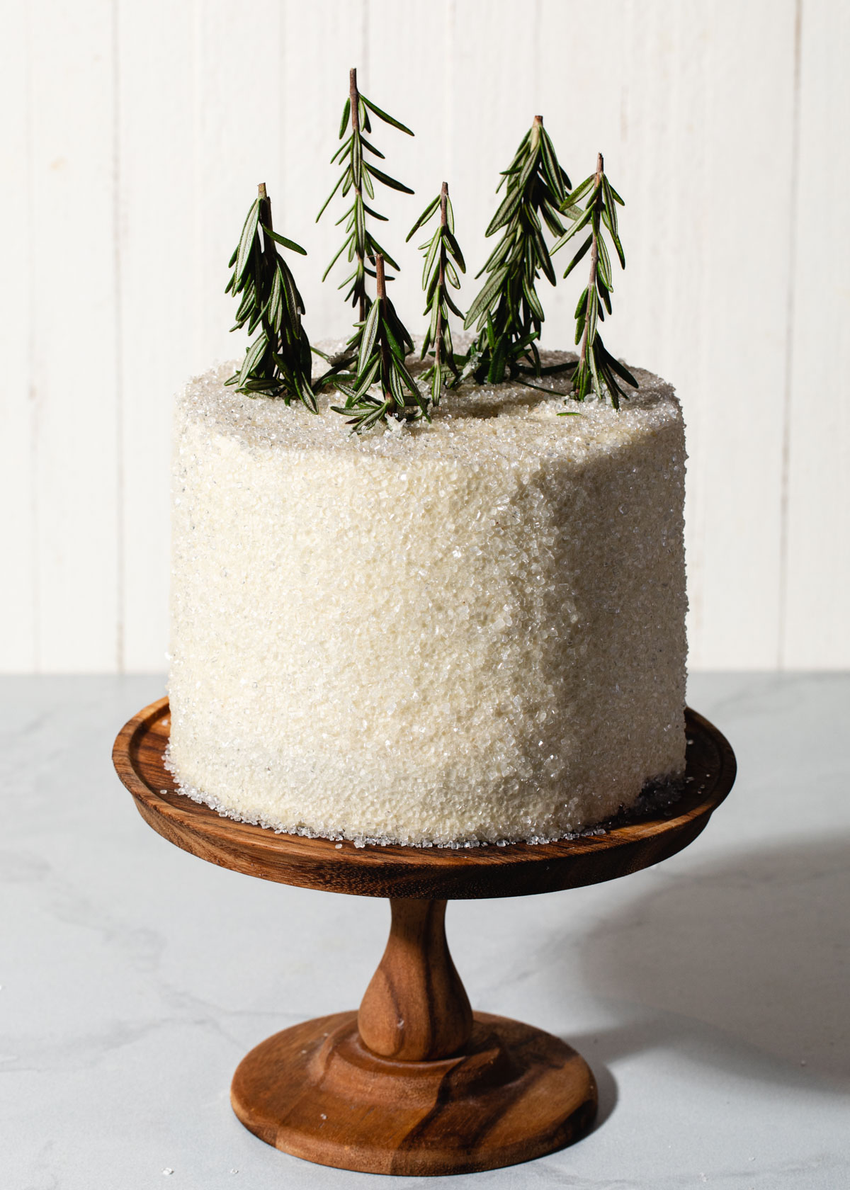 A chocolate layer cake with glittery sugar outside and rosemary sprigs on top.