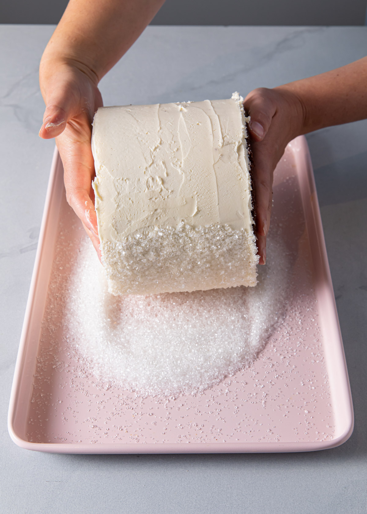 Adding sprinkles to the sides of a frosted cake