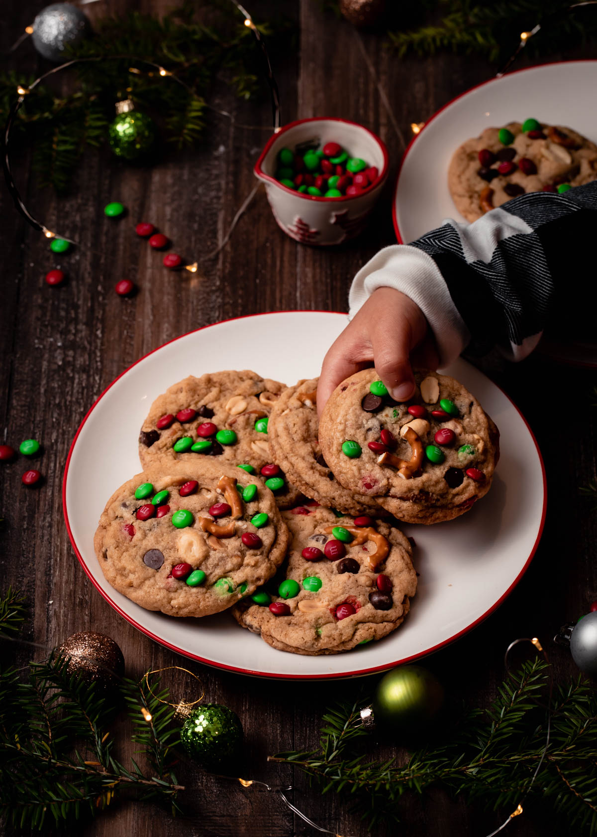 A child reaching for a Christmas cookie with red and green mini m&ms