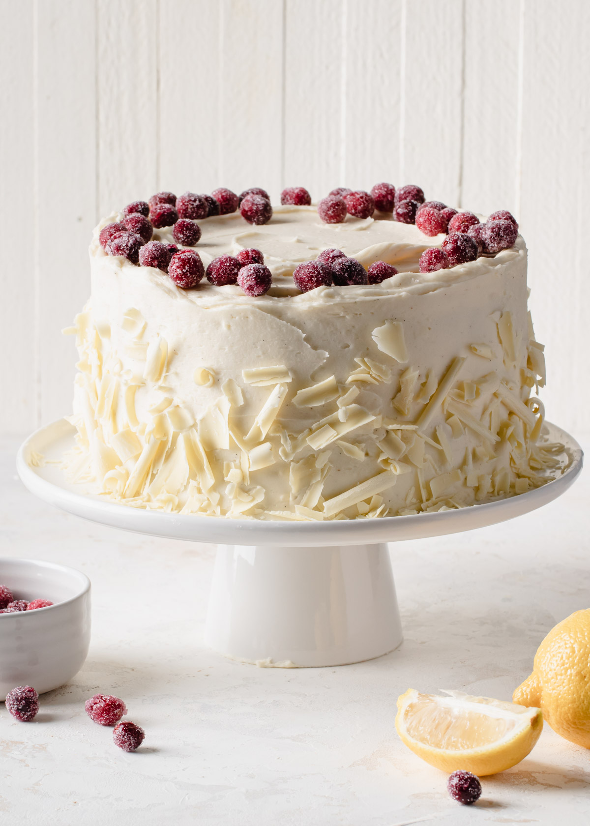 A lemon cake iced with cream cheese frosting and while chocolate curls around the sides 