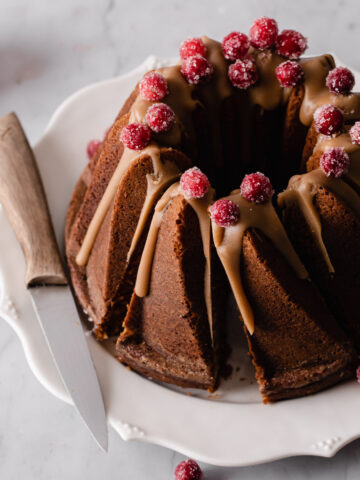 A gingerbread bundt cake with butterscotch glaze on top and sugared cranberries