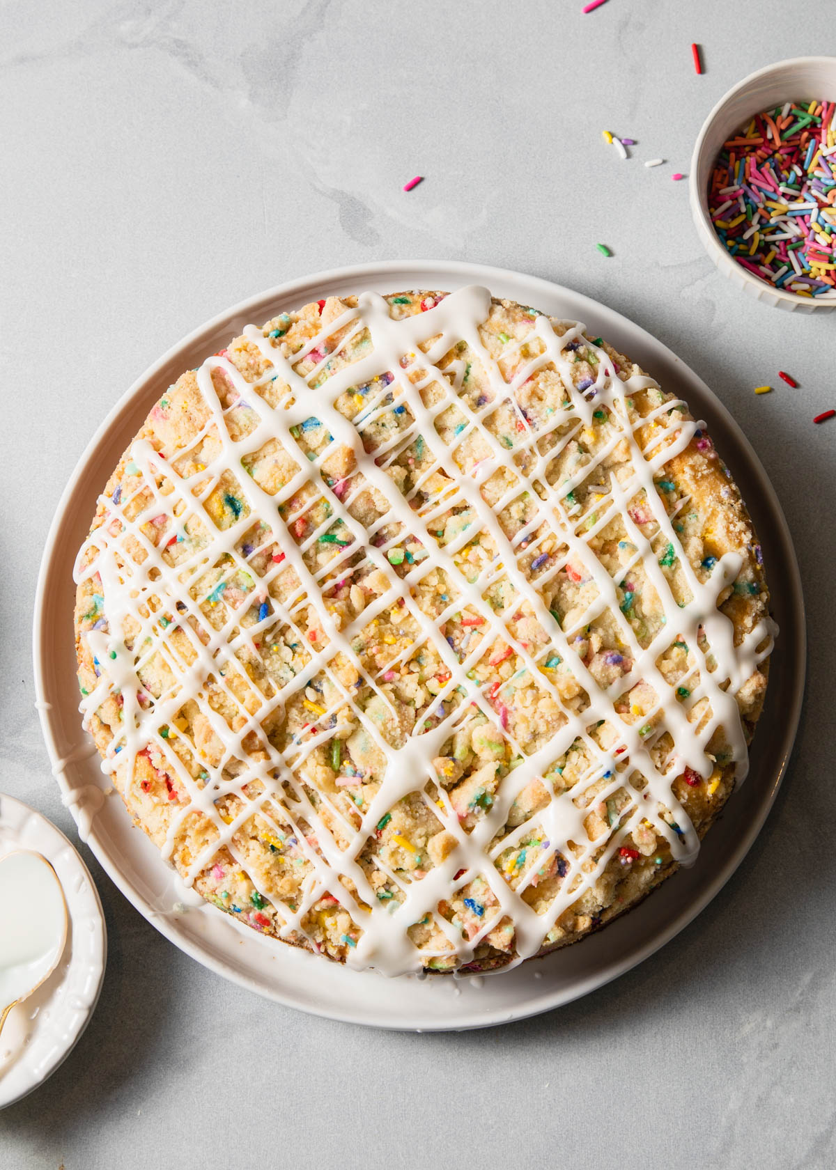 A coffee cake with sprinkles on top and vanilla glaze