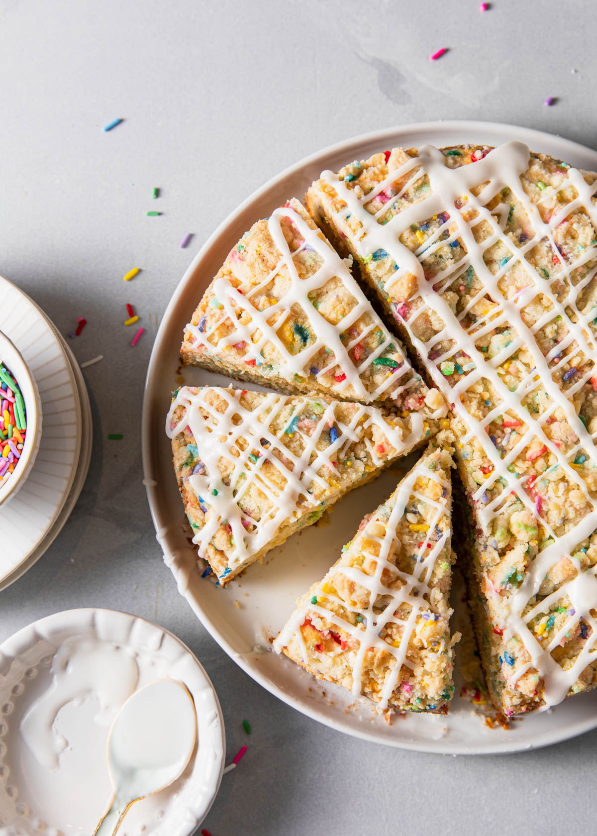 A birthday coffee cake with sprinkles and vanilla glaze on top.