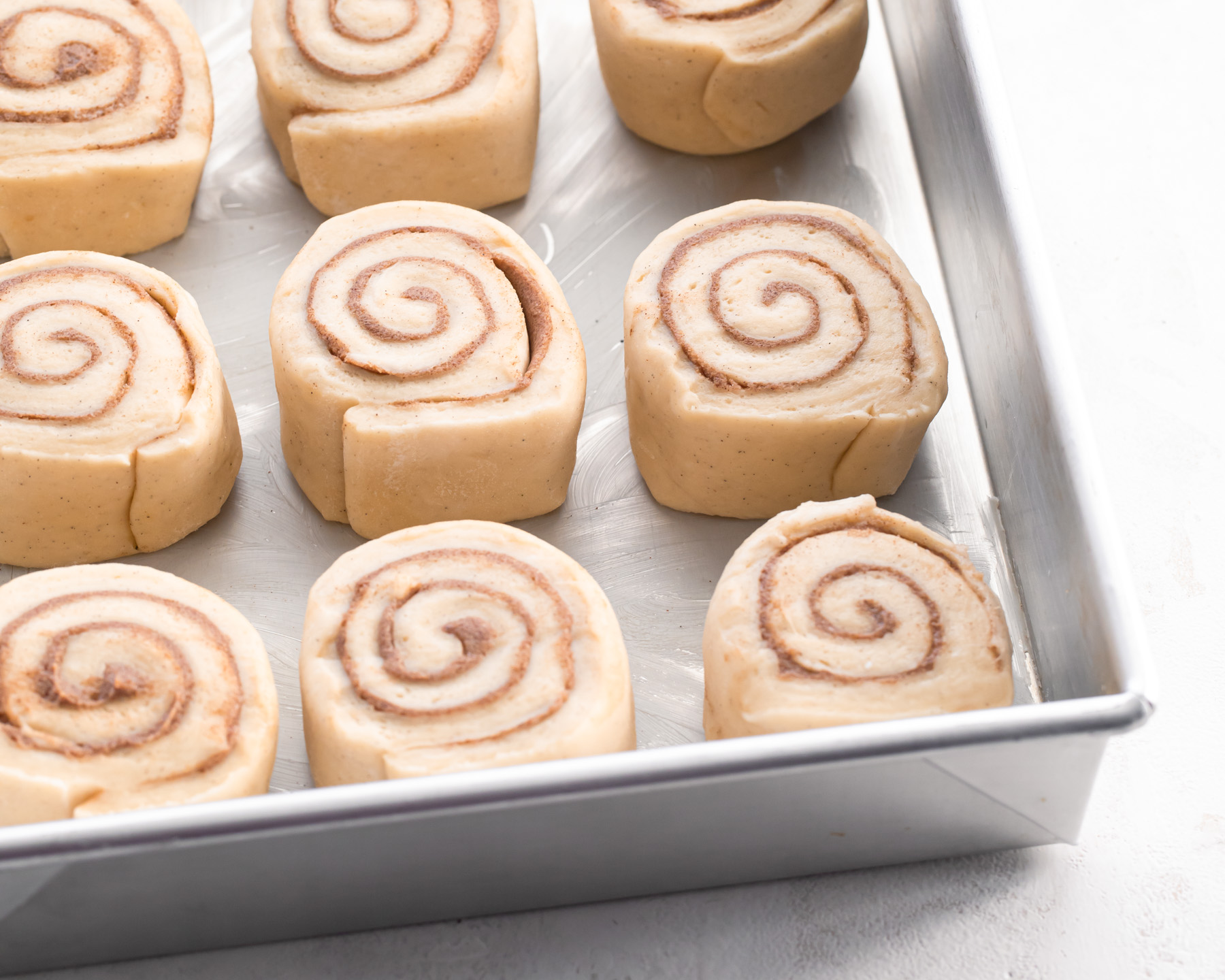 Unbaked cinnamon rolls proofing in their pan.