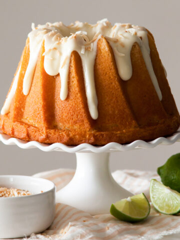 lemon olive oil cake on a cake stand with coconut glaze on top