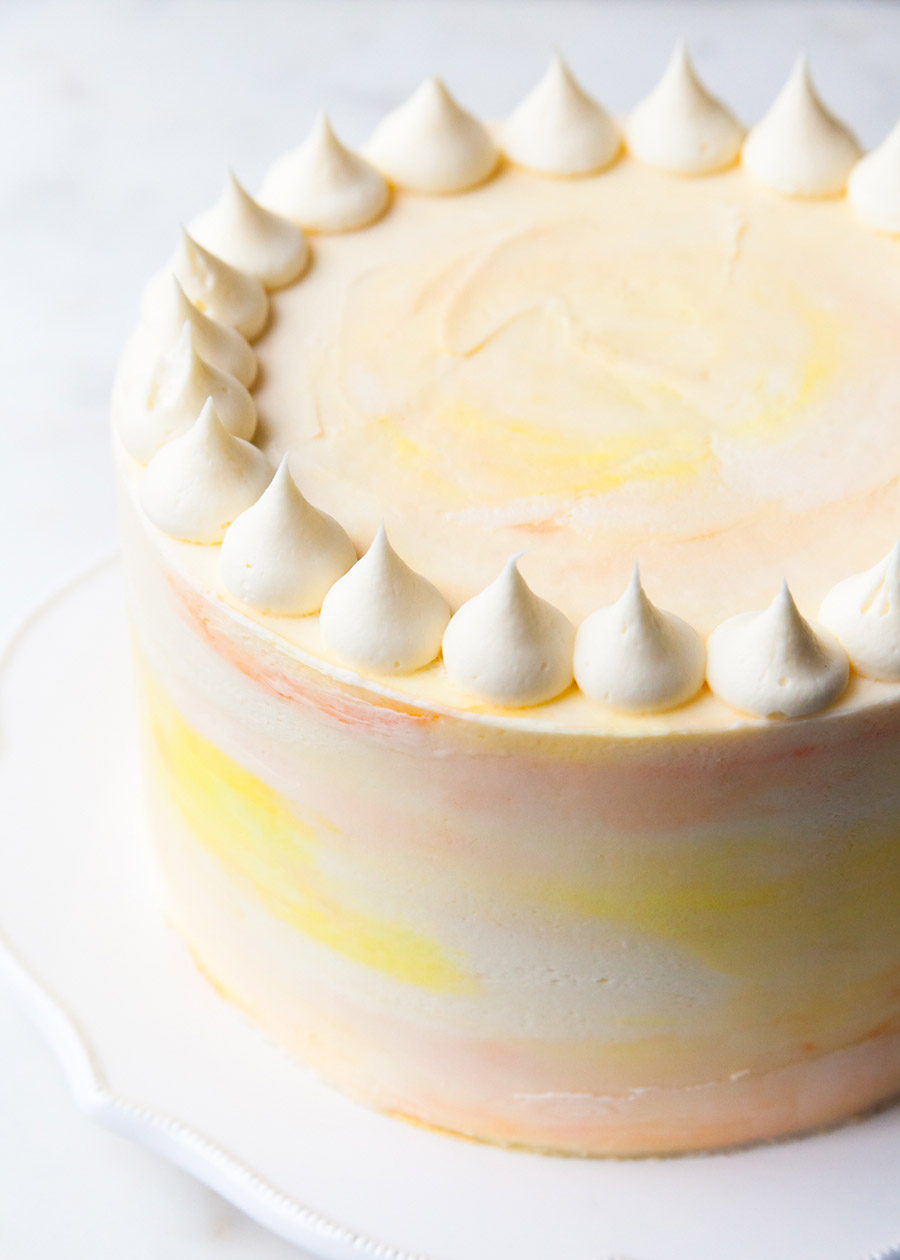 A beautifully decorated passion fruit cake with watercolor buttercream and piping on top
