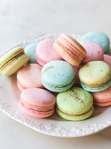 A platter of pastel macarons filled with raspberry buttercream.