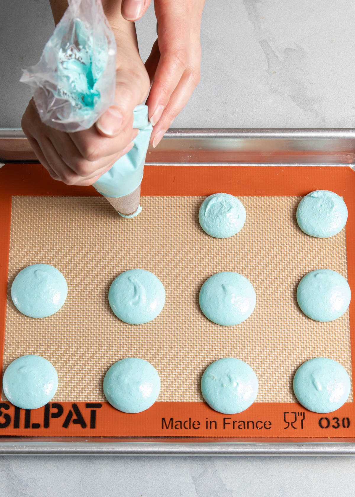 Piping French macarons on a baking sheet
