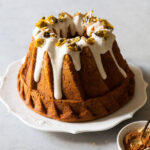 A pumpkin bundt cake with cream cheese glaze and pumpkin seed brittle on top