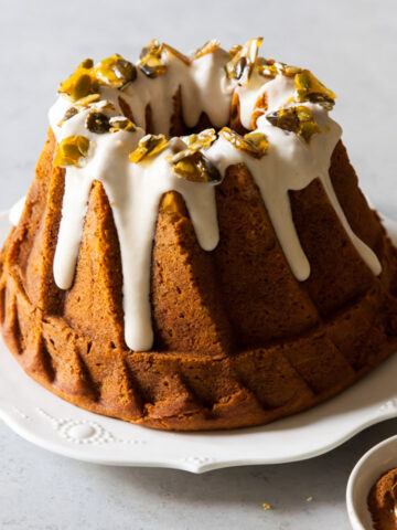 A pumpkin bundt cake with cream cheese glaze and pumpkin seed brittle on top