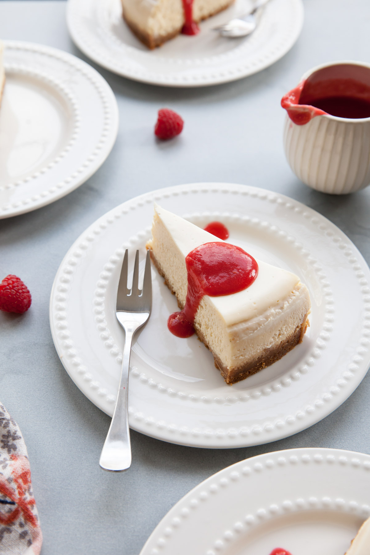 A slice of vanilla cheesecake with raspberry coulis on top