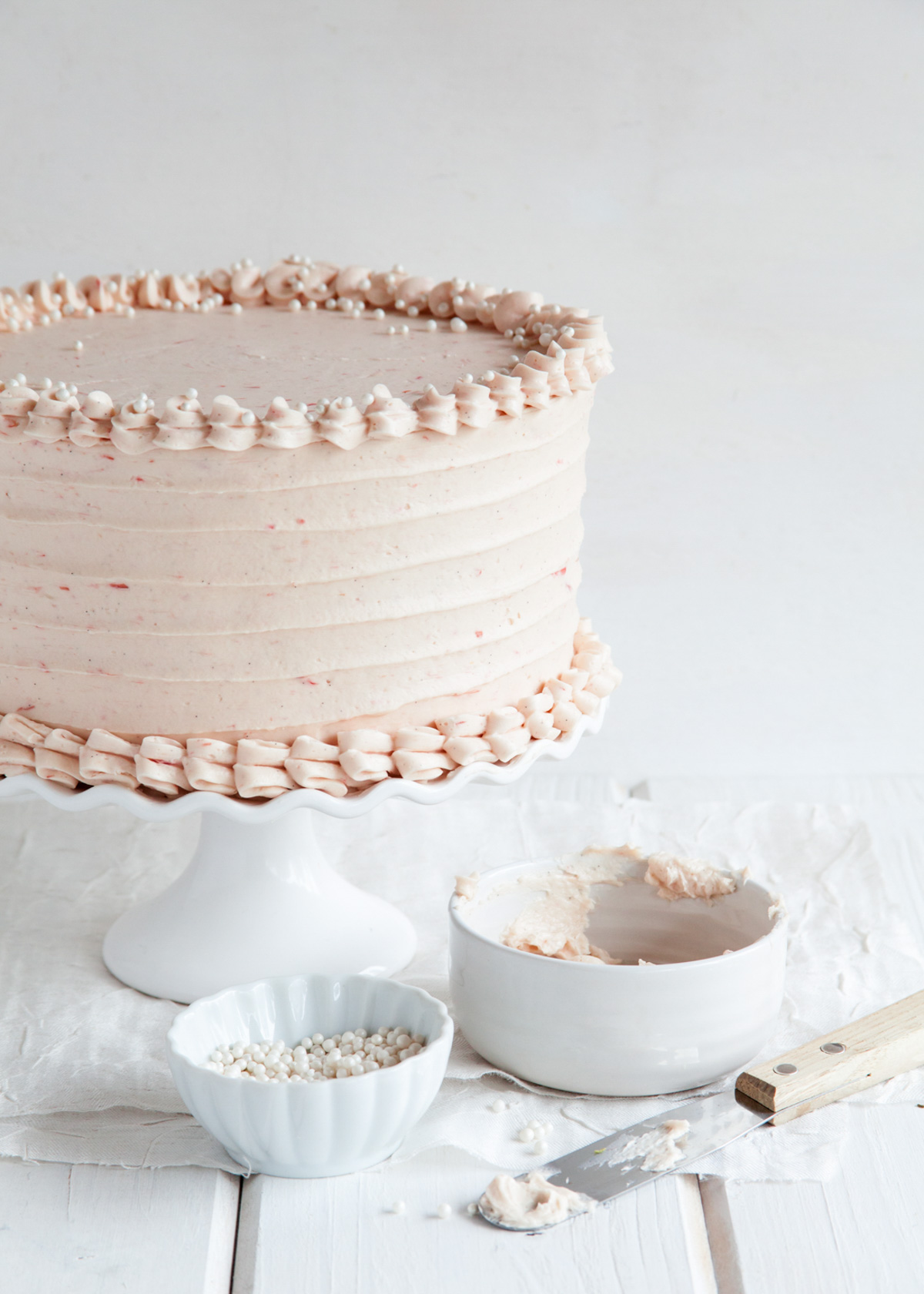 A pink rhubarb ginger cake on a white cake stand.
