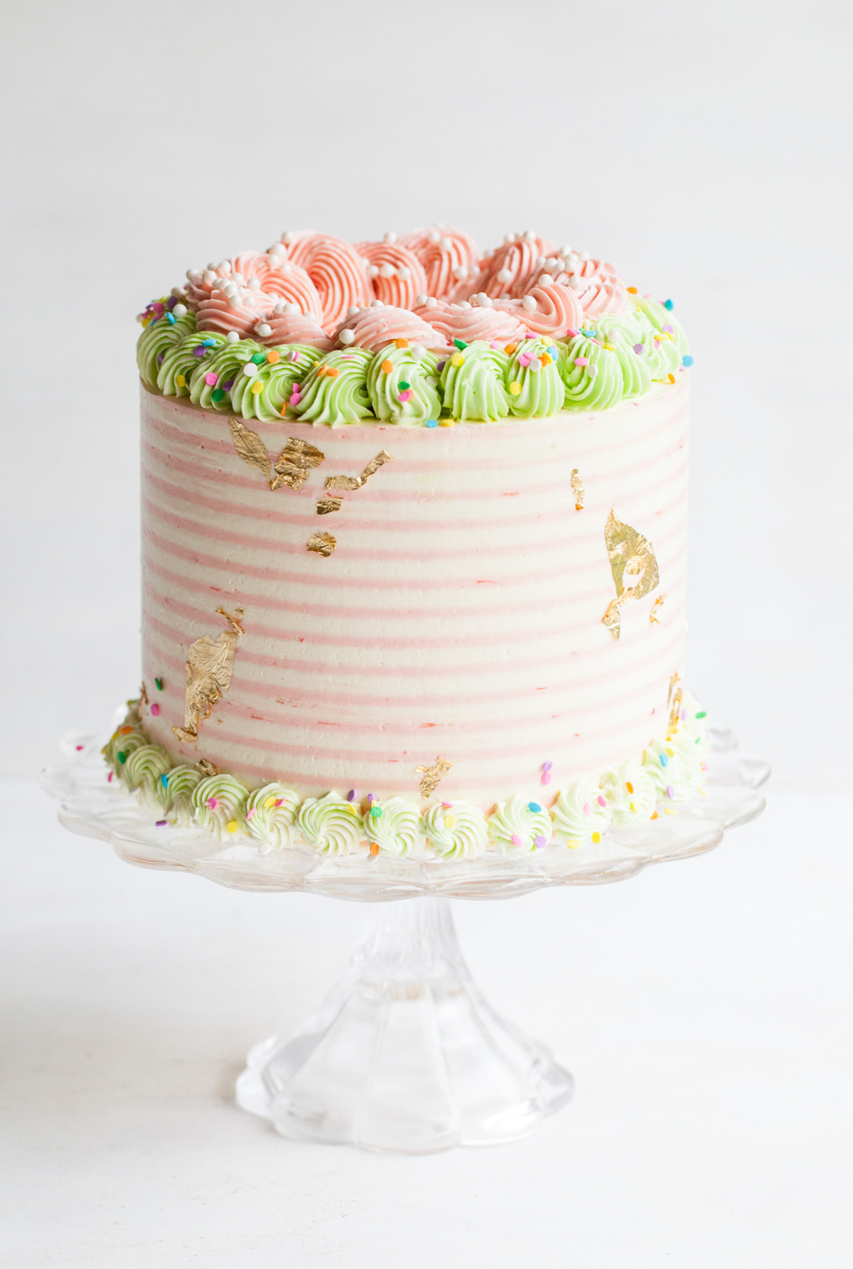 Rhubarb cake with pink and white striped buttercream and pastel piped borders