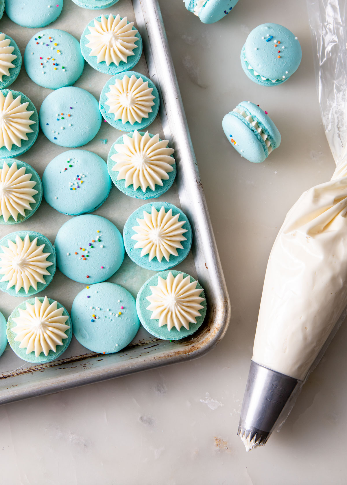 Piping vanilla frosting onto French macarons