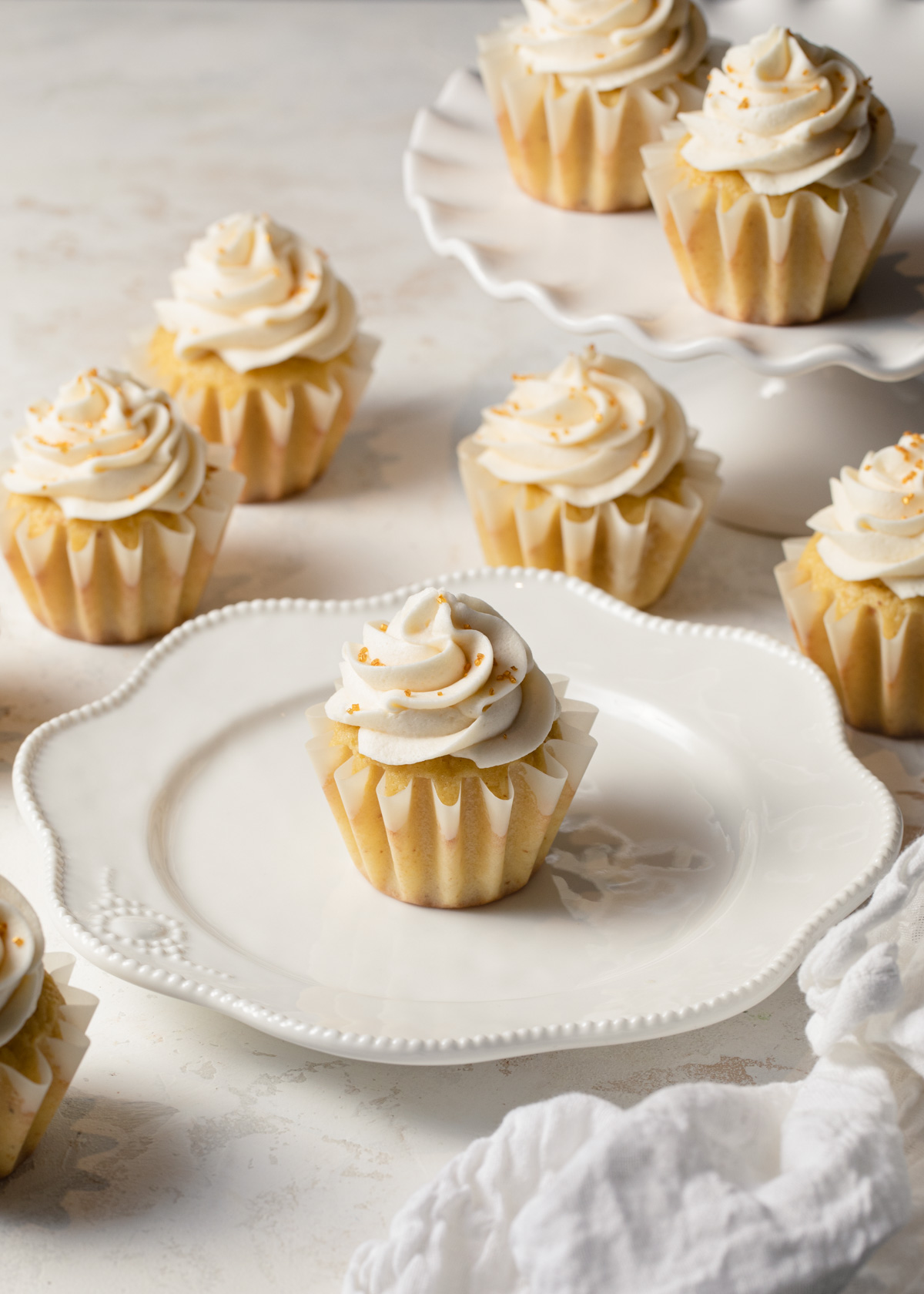 Vanilla cupcakes made with brown butter set on white plates and cake stands.
