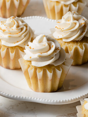 A plate of brown butter cupcakes with swirls of whipped buttercream on top