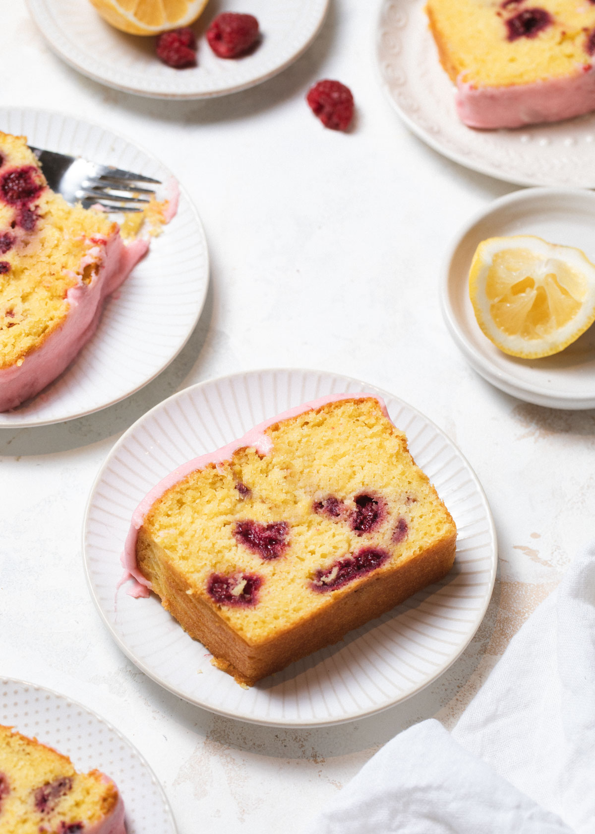 White plates with slices of raspberry lemon cake with pink glaze on top